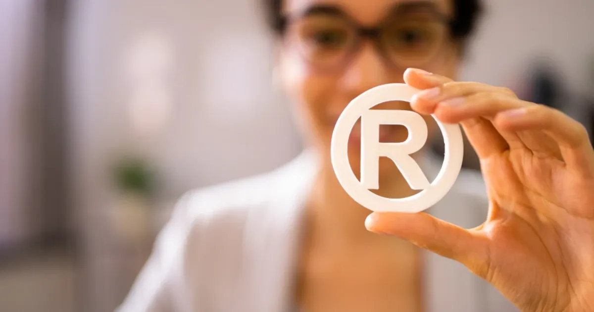 A woman holding up a registered trademark symbol | Trademark Engine